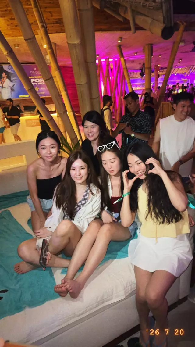 Four friends posing on a daybed at a beach club